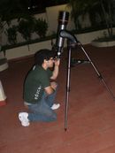 Aluno observa o céu utilizando telescópio.
