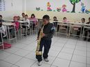 Aluno Natanael toca saxofone na sala de aula
