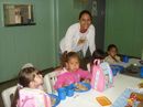 Professora Evelin dos Santos com alunos comendo merenda