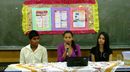 Três alunos sentados durante apresentação na sala de aula