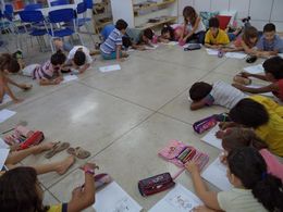 Alunos realizam atividades no chão da sala de aula