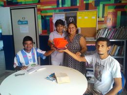 Teca Lima, o educador cultural Pedro e dois assistidos do Centro Pop seguram o troféu do Prêmio Viva Leitura