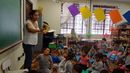 Cristiane Souza, mãe de estudante, lê um livro na sala de aula 
